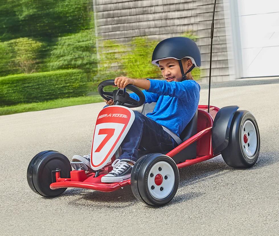 Kid riding on his first electric go kart in front of a house