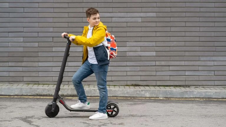 Young boy riding an e-scooter on a public road